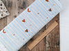 Little birds and squirrels with hats and jumpers on climbing birch trees on light blue snowy cotton fabric
